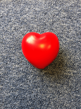 Picture of a heart-shaped stress ball against a blue and grey carpet.